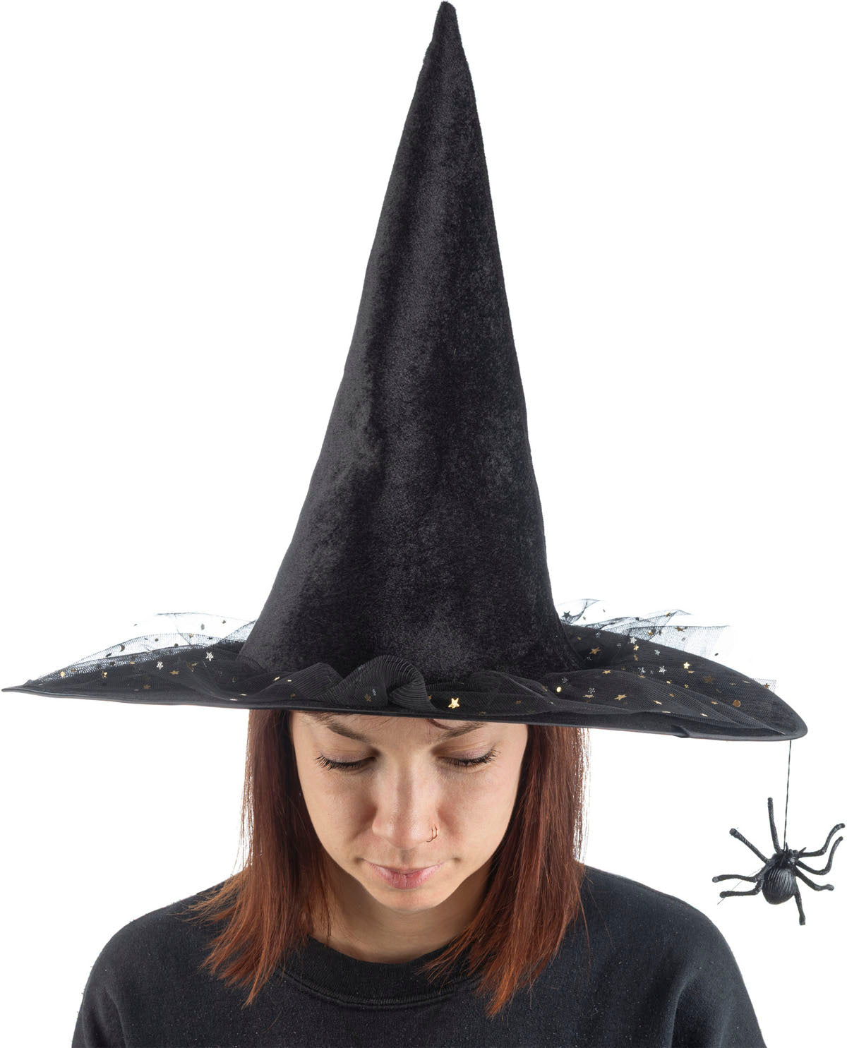 A woman wearing a tall black pointed witch hat with a wide brim, black tattered netting, and a dangling black spider decoration, shown against a plain white background.