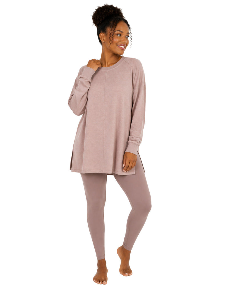 A woman modeling a matching long-sleeve tunic top and leggings set in a dusty mauve-pink color, standing against a plain white background.