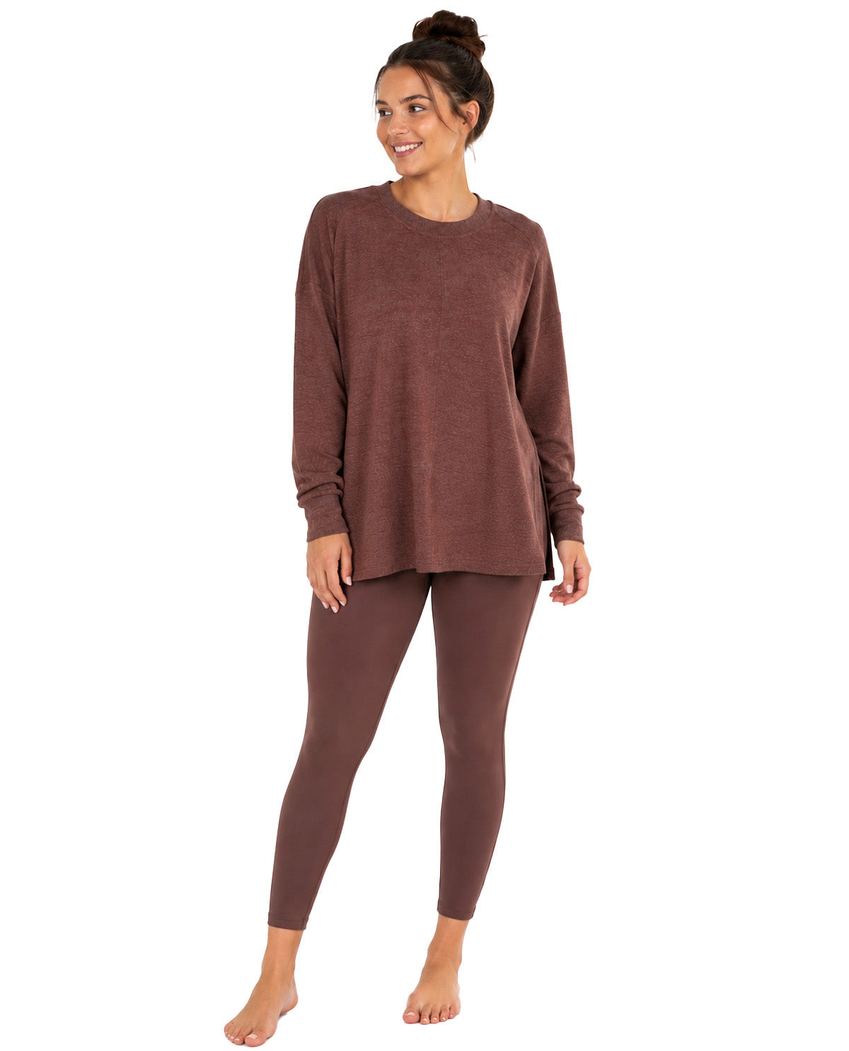 A woman modeling a matching two-piece loungewear set consisting of a long-sleeve crewneck top and full-length leggings in a heathered brown color, shot against a plain white background.