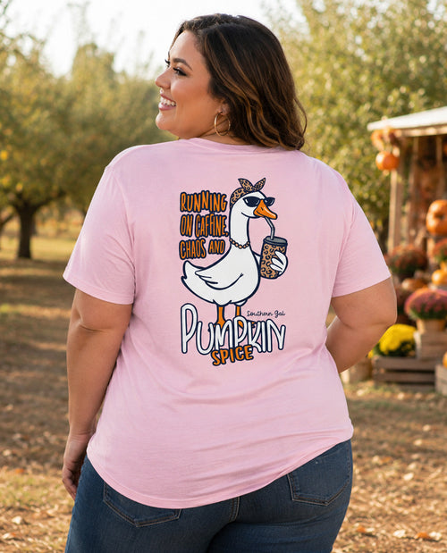 Woman model wearing a short sleeve lt pink tee with graphic "RUNNING ON CAFFINE CHAOS AND PUMPKIN SPICE" with a goose print