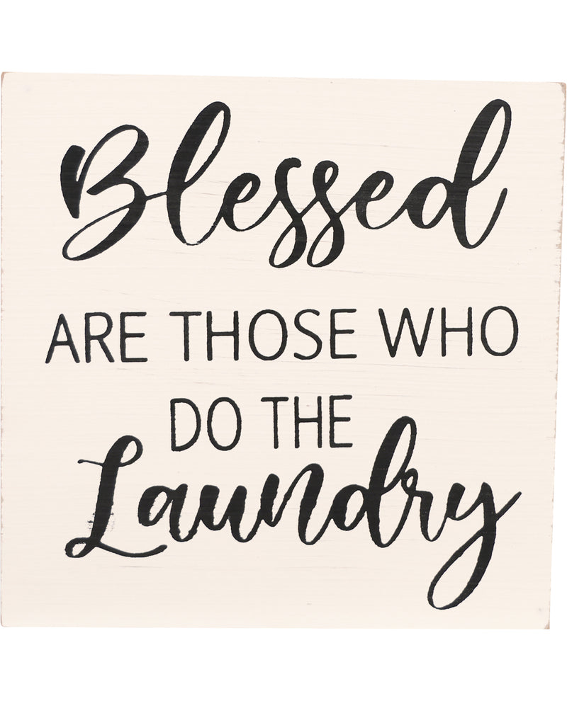 A rectangular cream-colored wooden sign with black painted text that reads, 'Blessed are those who do the laundry.'
