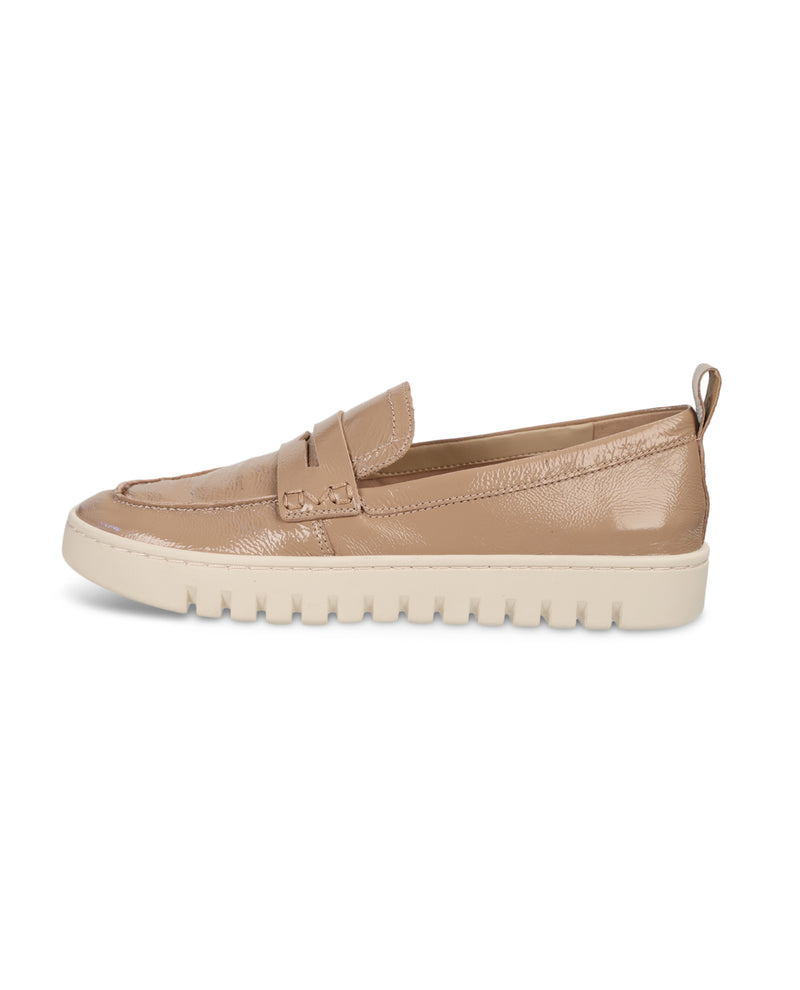 A single tan leather slip-on loafer with a textured finish, featuring a thick, ridged off-white sole, shown from a side profile on a white background.