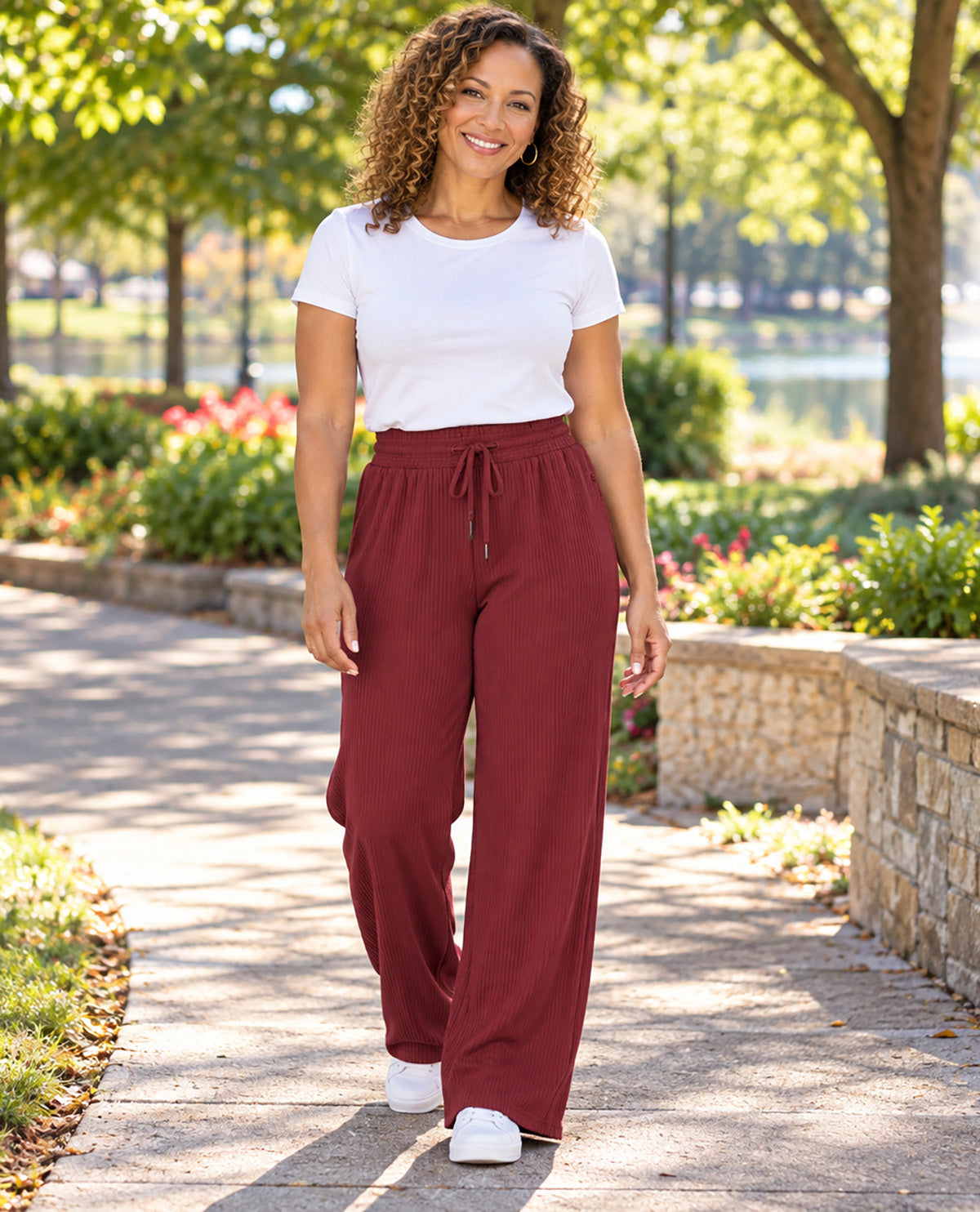 Missy model wearing burgundy pants with a white tee tucked in with an outdoor background