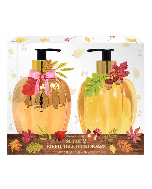 A boxed set of two refillable hand soaps shaped like metallic gold pumpkins, displayed in a clear-front package with autumn leaf and acorn decorations. The front label reads 'The Art of Living Set of 2 Refillable Hand Soaps'.