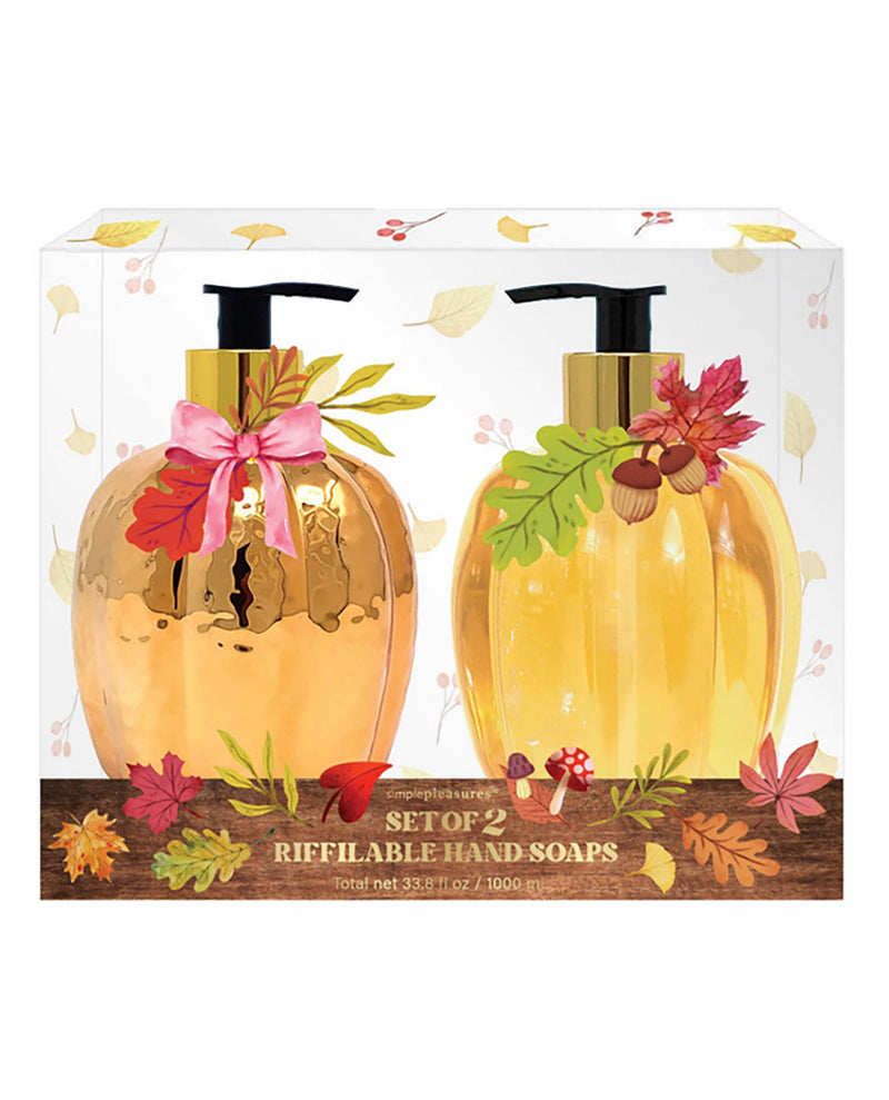 A boxed set of two refillable hand soaps shaped like metallic gold pumpkins, displayed in a clear-front package with autumn leaf and acorn decorations. The front label reads 'The Art of Living Set of 2 Refillable Hand Soaps'.