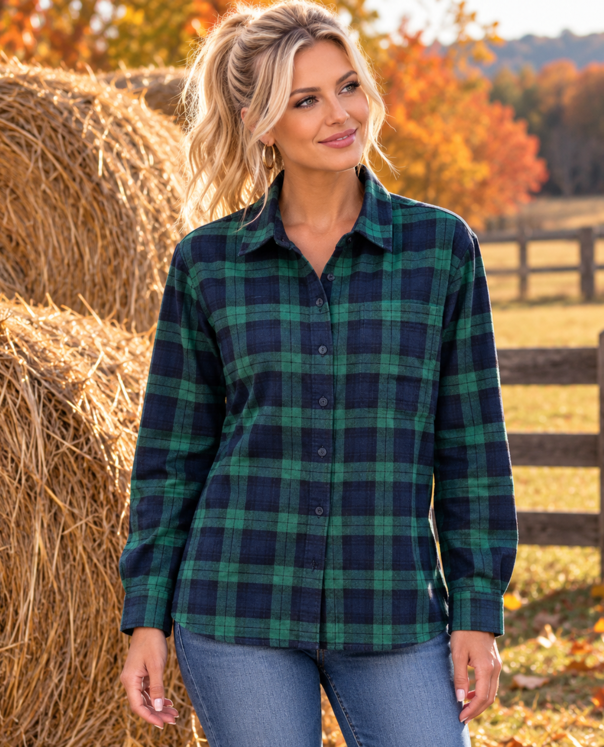 A woman wearing a green and navy blue plaid button-up shirt, standing outdoors in front of hay bales and an autumn landscape.