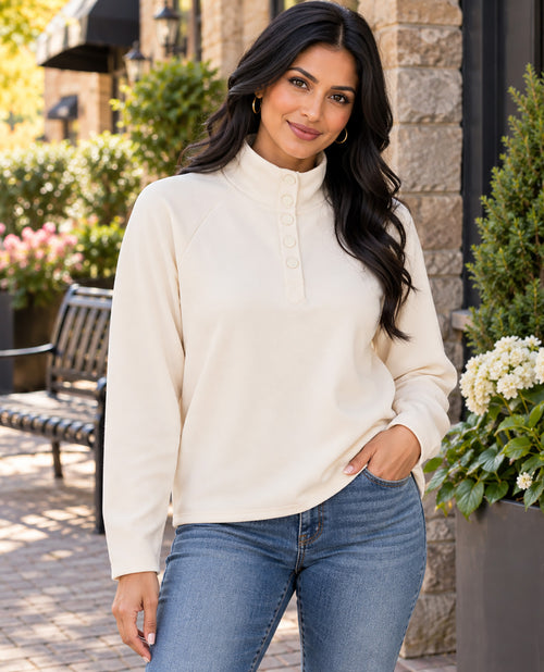 Missy model wearing an ivory long sleeve mock neck top paired with jeans with an outdoor background