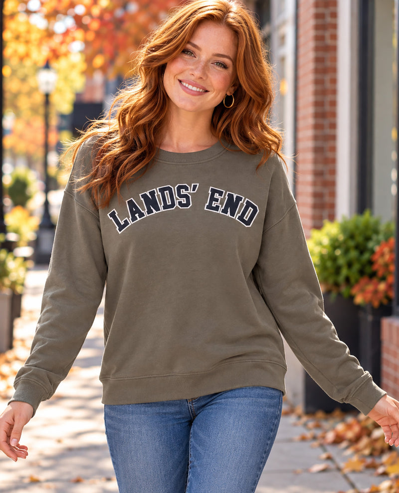Missy model wearing a green long sleeve shirt with a graphic "LANDS' END" across the chest paired with jeans with an outdoor background