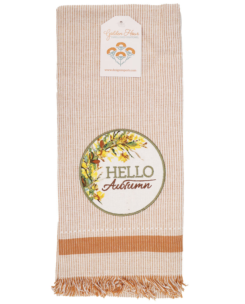 A striped kitchen towel with fringe, featuring a circular 'Hello Autumn' floral design and a hanging paper tag for 'Golden Hours'.