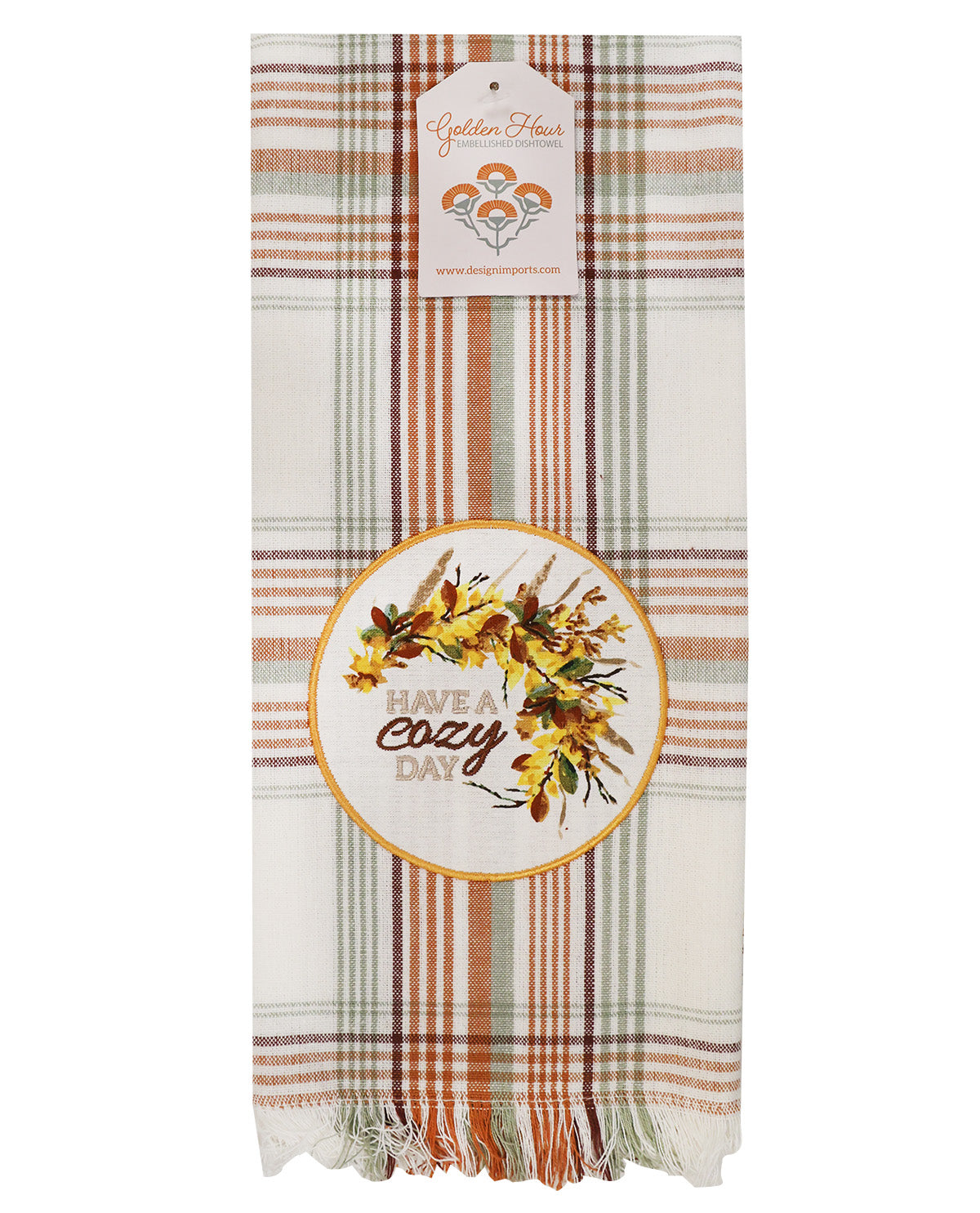 A plaid throw blanket with fringe at the bottom, featuring a warm autumn color palette of beige, rust orange, brown, and sage green. It has a circular embroidered patch in the center reading 'cozy day' with a floral wreath design, and a hanging tag for 'Golden House'.
