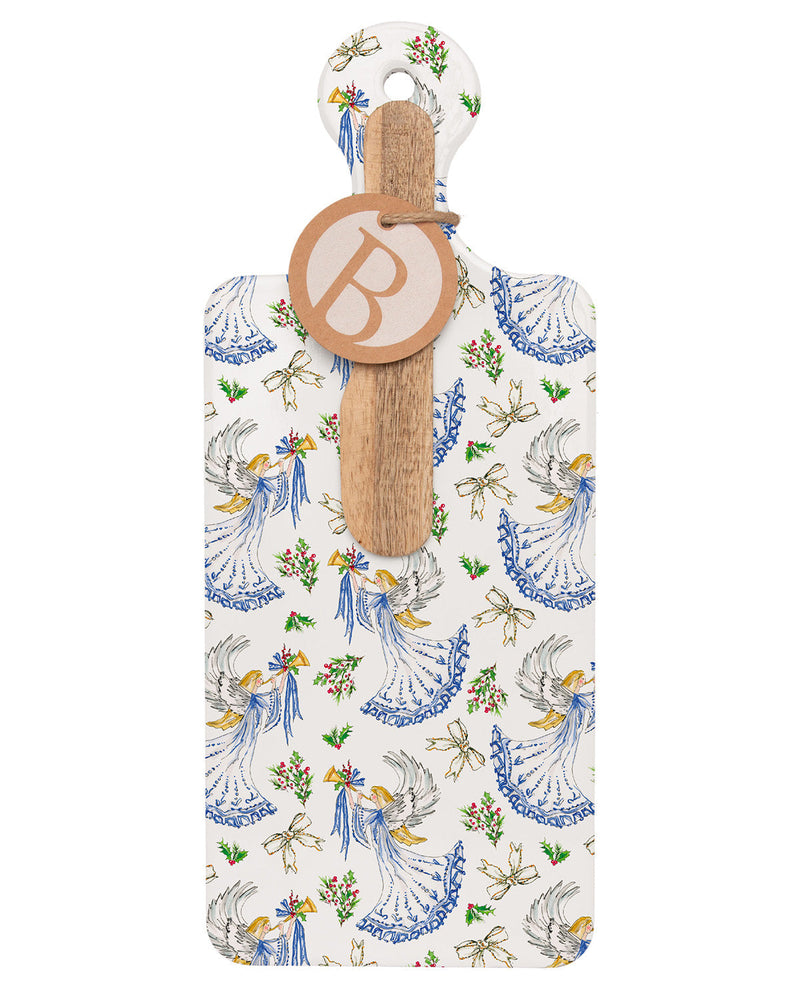 A rectangular wooden serving board or tray with a hanging wooden handle, featuring an all-over toile-style print of blue angels, white doves, and small floral motifs on an off-white background. A round wooden tag with a monogram letter 'B' is attached to the handle.