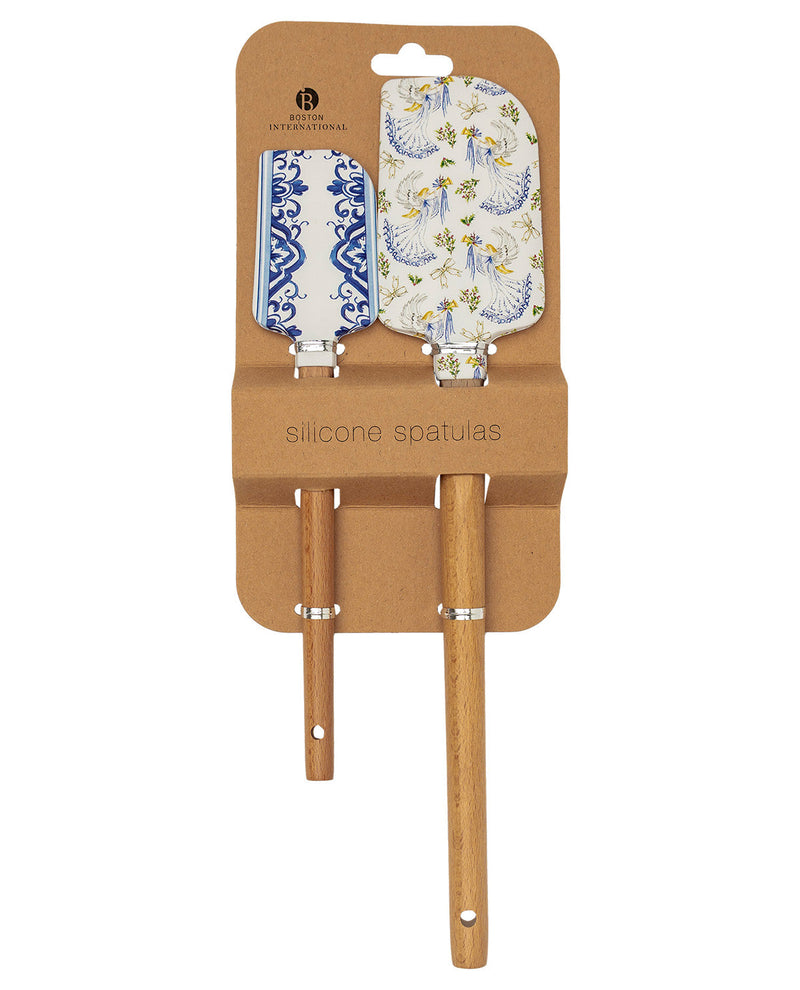 Two silicone spatulas with wooden handles and decorative blades, packaged on a brown cardboard backing. One spatula has a blue and white floral pattern, and the other has a blue and white scroll pattern on a white background.