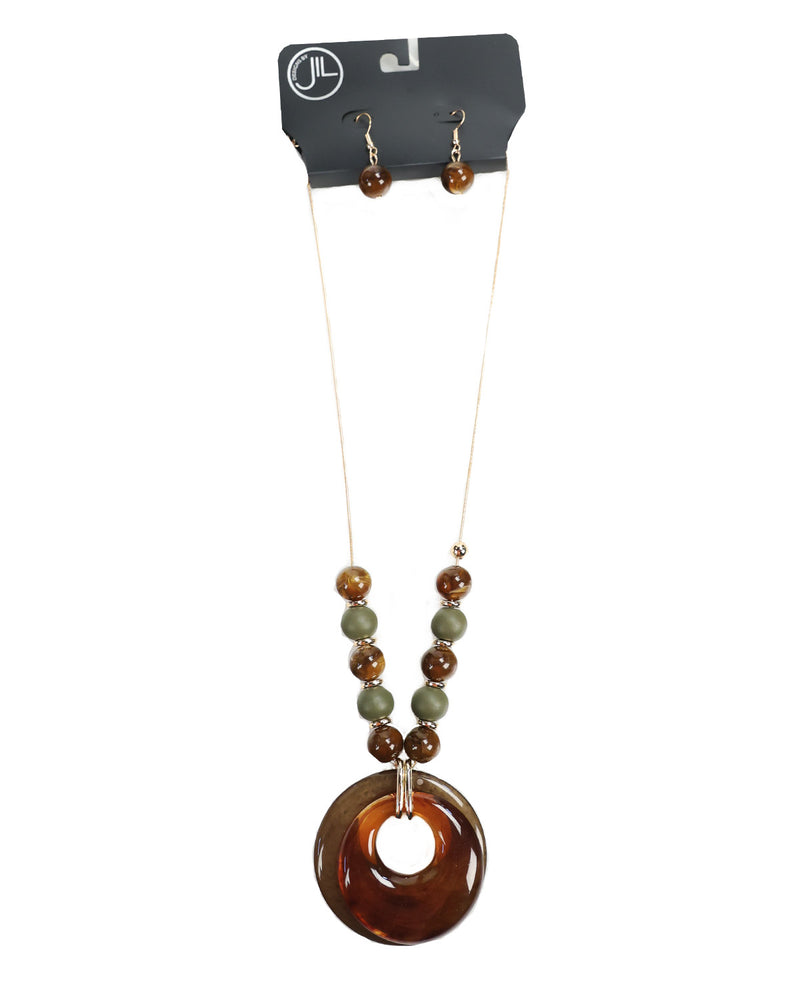 A beaded necklace and matching drop earrings displayed on a black retail card. The necklace has a large translucent amber-brown donut pendant with smaller brown and olive green beads, and the matching earrings have small brown beads and gold hooks.
