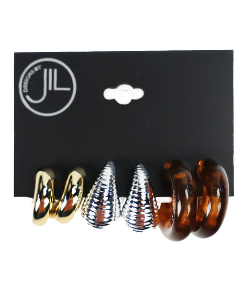 Three pairs of spiral hoop earrings displayed on a black backing card. The left pair is metallic gold, the middle pair is metallic silver with a textured pattern, and the right pair is translucent amber brown.