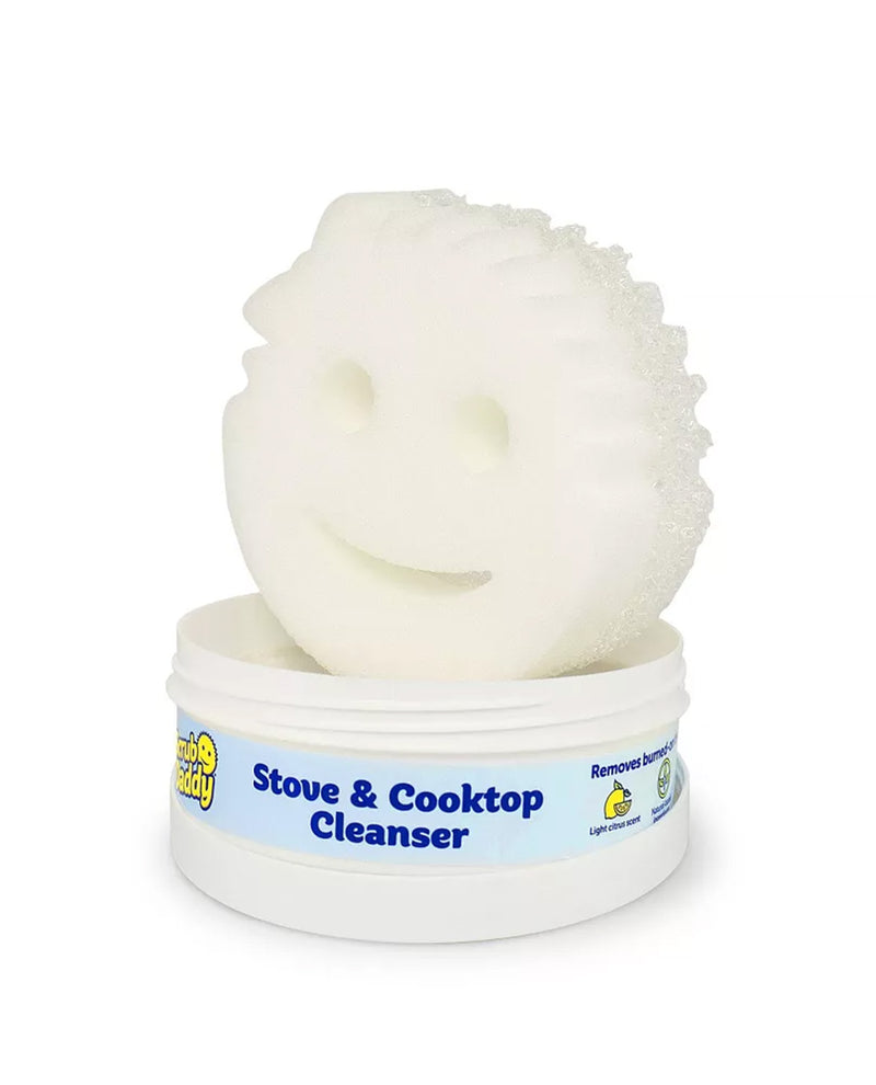 A white textured cleaning sponge with a smiley face cutout, resting on top of a white plastic tub labeled 'Stove & Cooktop Cleanser' by Lemon Scout.