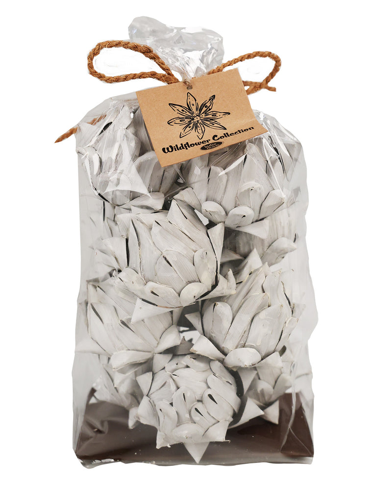 A clear plastic bag filled with white artificial flower petals or faux blossoms, tied with a brown twine bow and a kraft paper tag that reads 'Wildflower Collections,' on a white background.