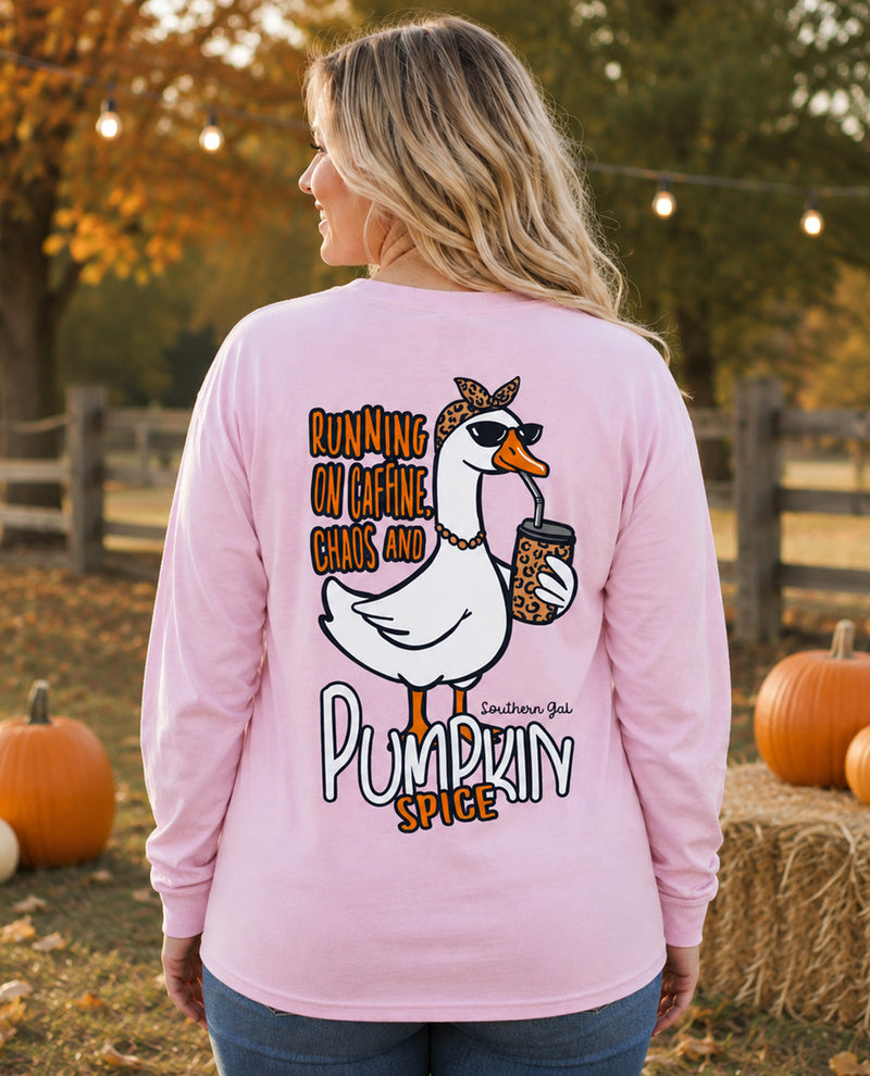 A woman shown from the back wearing a light pink long-sleeve shirt with a large graphic on the back. The graphic features a white goose wearing sunglasses and a leopard-print headband, holding a coffee mug, with the text 'RUNNING ON CAFFEINE CHAOS AND PUMPKIN SPICE'.