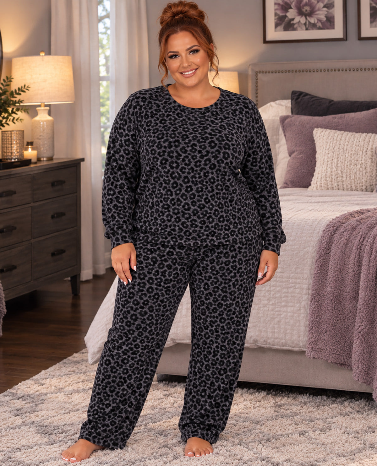 A woman modeling a matching two-piece pajama set with a dark gray and black leopard print, standing in a bedroom setting.