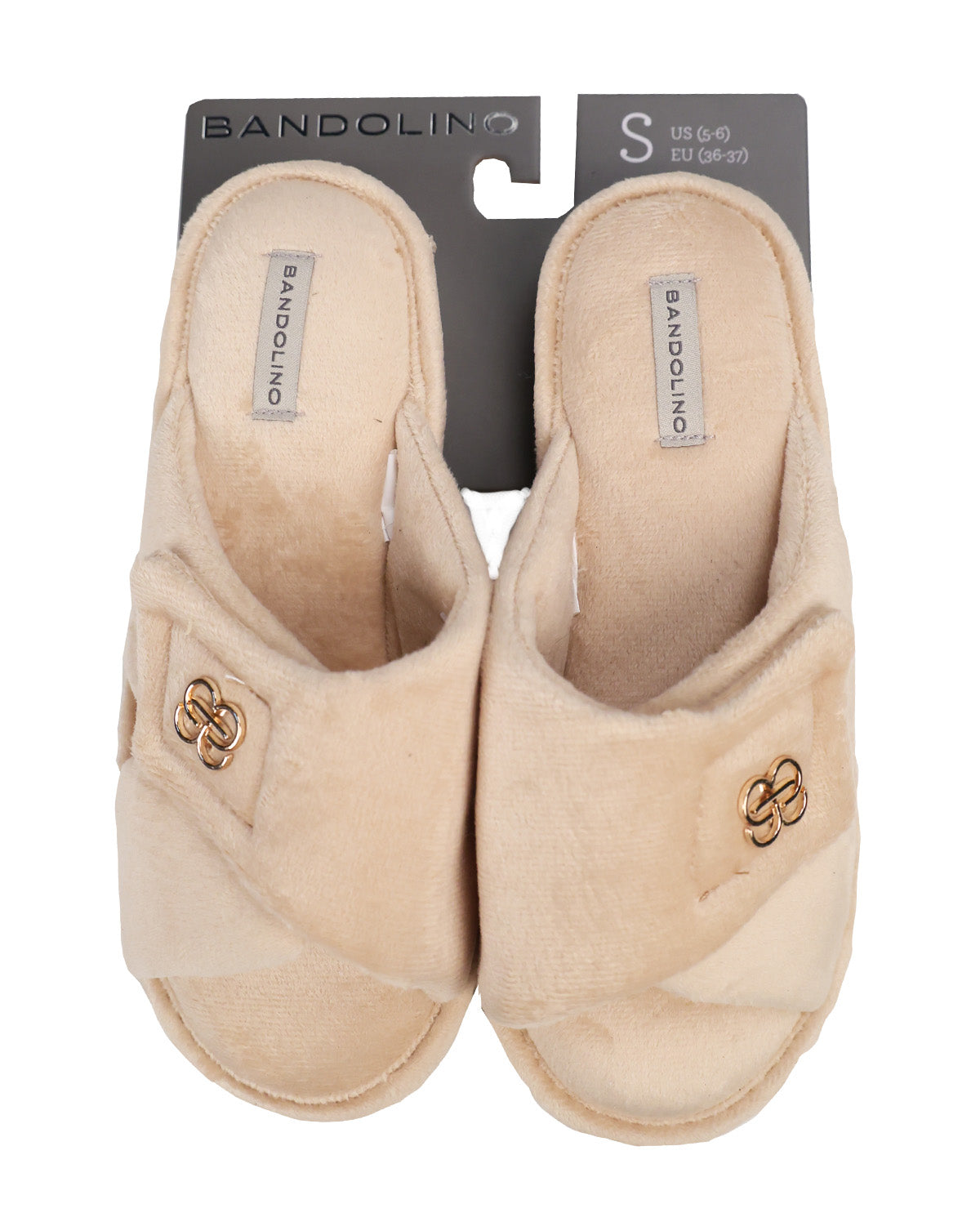 A pair of Bandolino beige plush slip-on slippers with gold-tone double-S logo embellishments, shown on their original dark gray retail hanger against a white background.