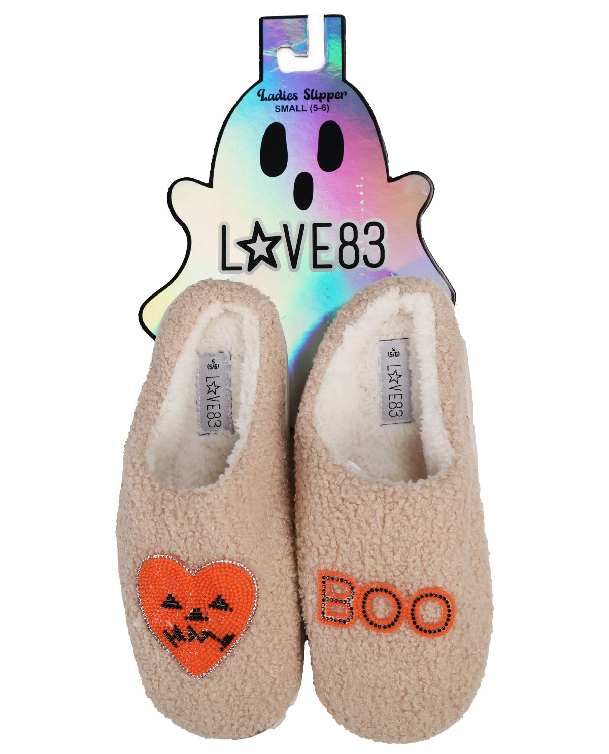 A pair of beige sherpa slip-on slippers with Halloween-themed embroidery, displayed on their holographic ghost-shaped packaging card. The left slipper features an orange beaded jack-o'-lantern heart, and the right slipper features the word 'BOO' in orange beads.