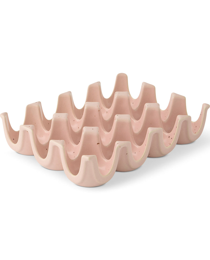 A wavy, multi-tiered ceramic dish rack in a light dusty pink color, shown on a clean white background.