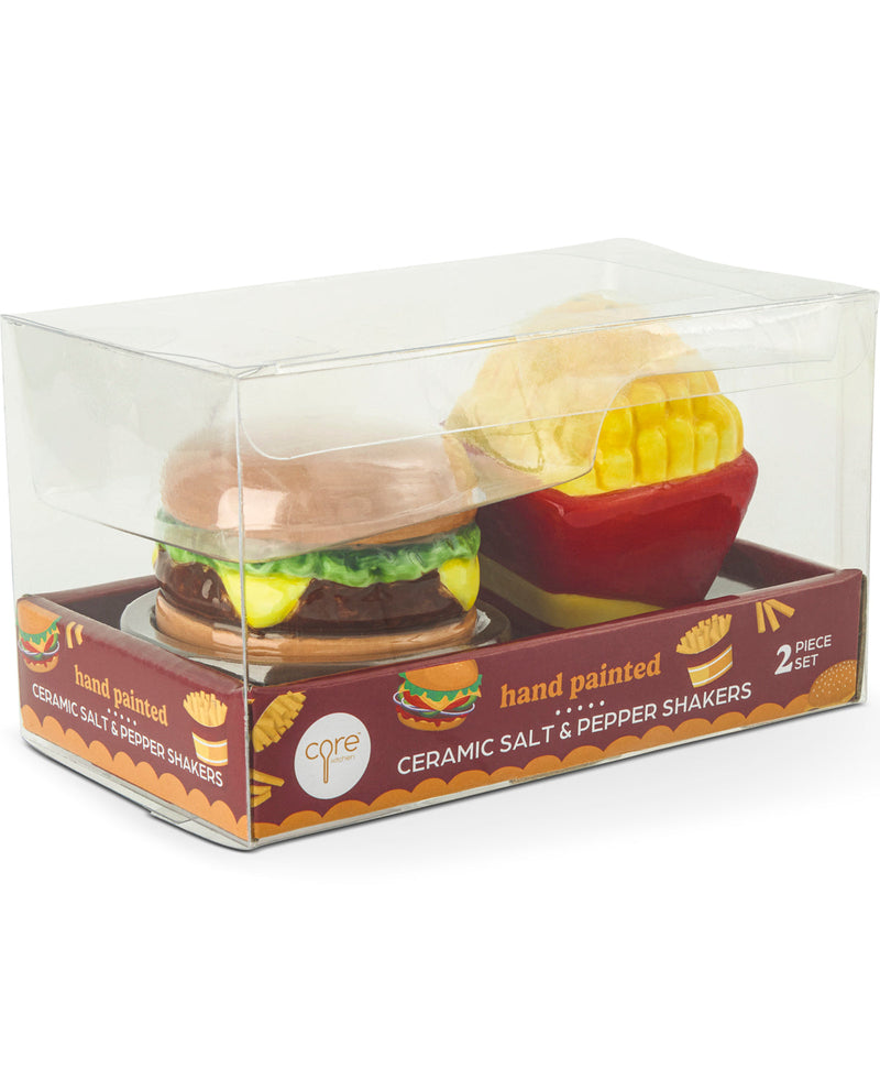 A 2-piece ceramic salt and pepper shaker set in its original clear plastic packaging box. The set includes a hand-painted hamburger and french fries.