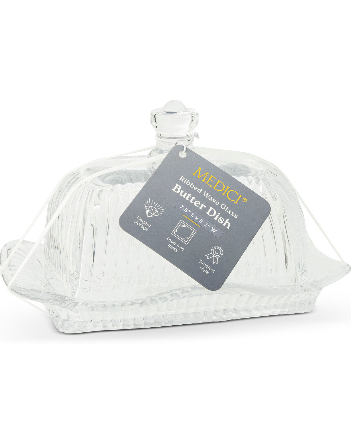 A clear ribbed glass butter dish with a matching lid and a hanging gray MEDICI product tag, photographed on a white background.