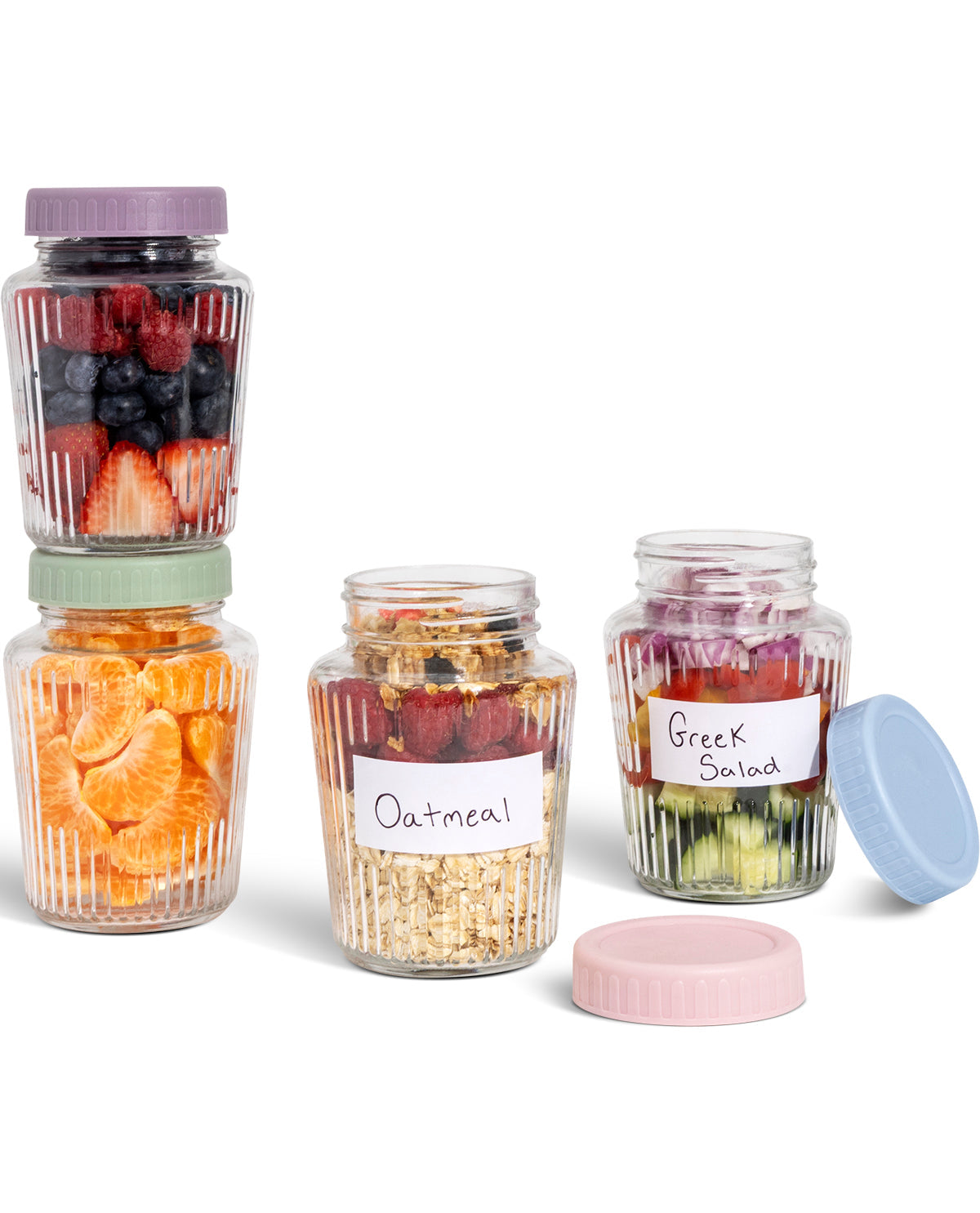 Four clear ribbed storage jars with lids in purple, mint green, white, and light blue, shown on a white background. Two jars are stacked with dried fruit and berries, one jar is filled with granola, and one jar is labeled Greek salad.