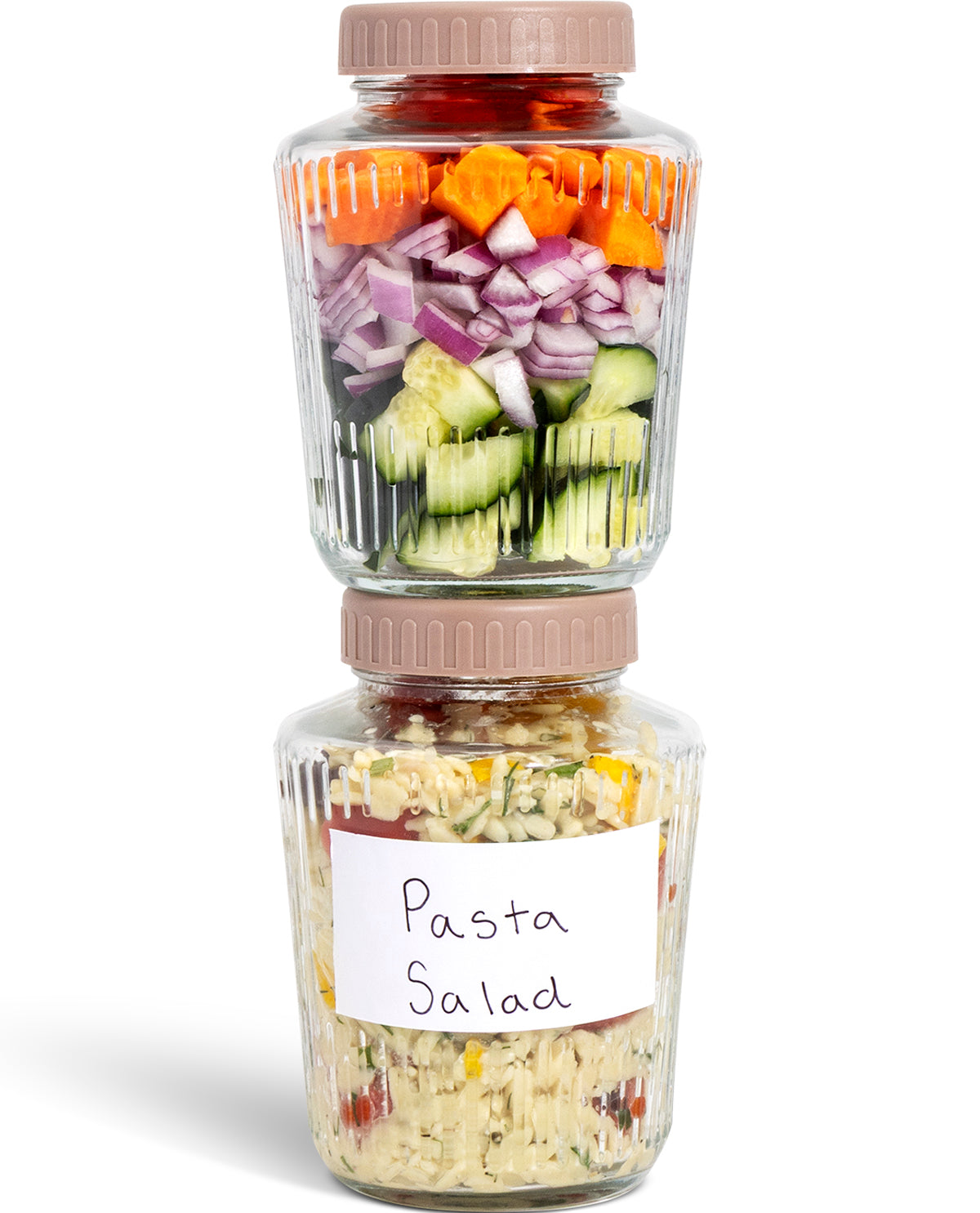 Two clear plastic food storage jars with beige screw-top lids stacked vertically on a white background. The top jar contains layered chopped vegetables including carrots, red onion, and cucumbers, while the bottom jar has a handwritten label reading 'Pasta Salad' and contains mixed pasta salad.