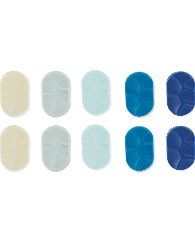 Twelve oval silicone or rubber grip pads arranged in two rows of six on a white background. The top row includes cream, pale gray, light blue, medium blue, and dark blue variants, while the bottom row shows matching pads with a textured, raised-seam pattern.