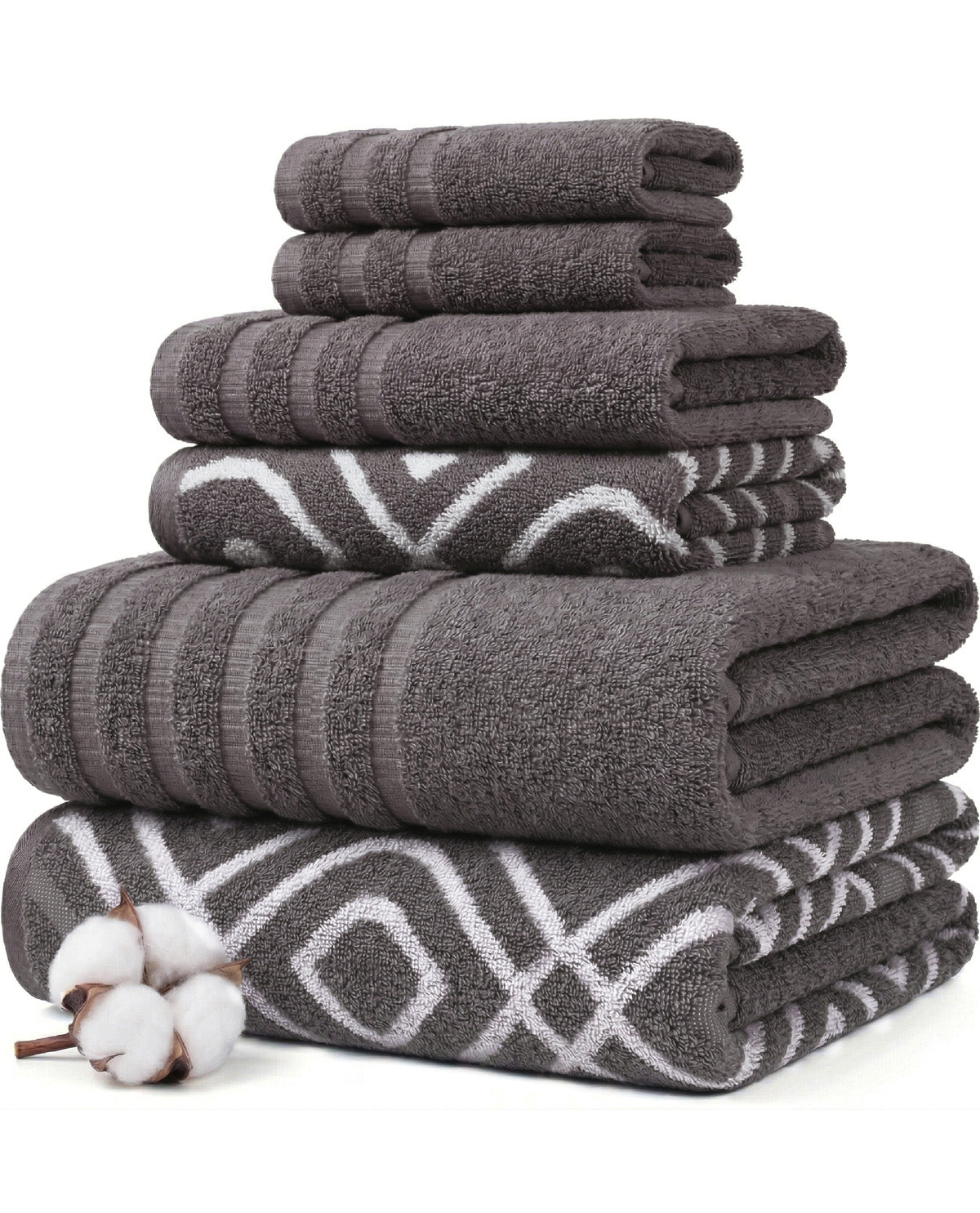 A stack of folded bath towels in dark gray and charcoal tones, including solid textured towels and patterned towels with white geometric designs. A small cotton boll is placed in the lower left corner on a clean white background.
