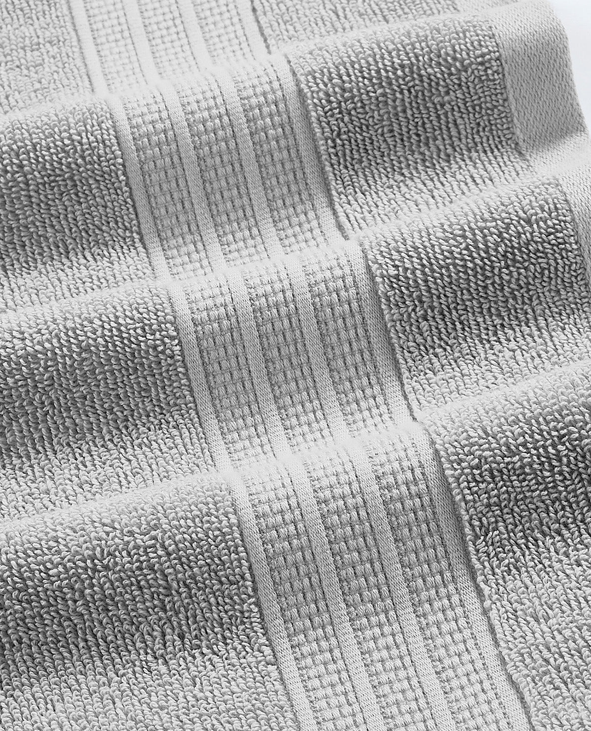 A close-up of a light gray textured towel with ribbed woven stripes and looped terry-like texture.
