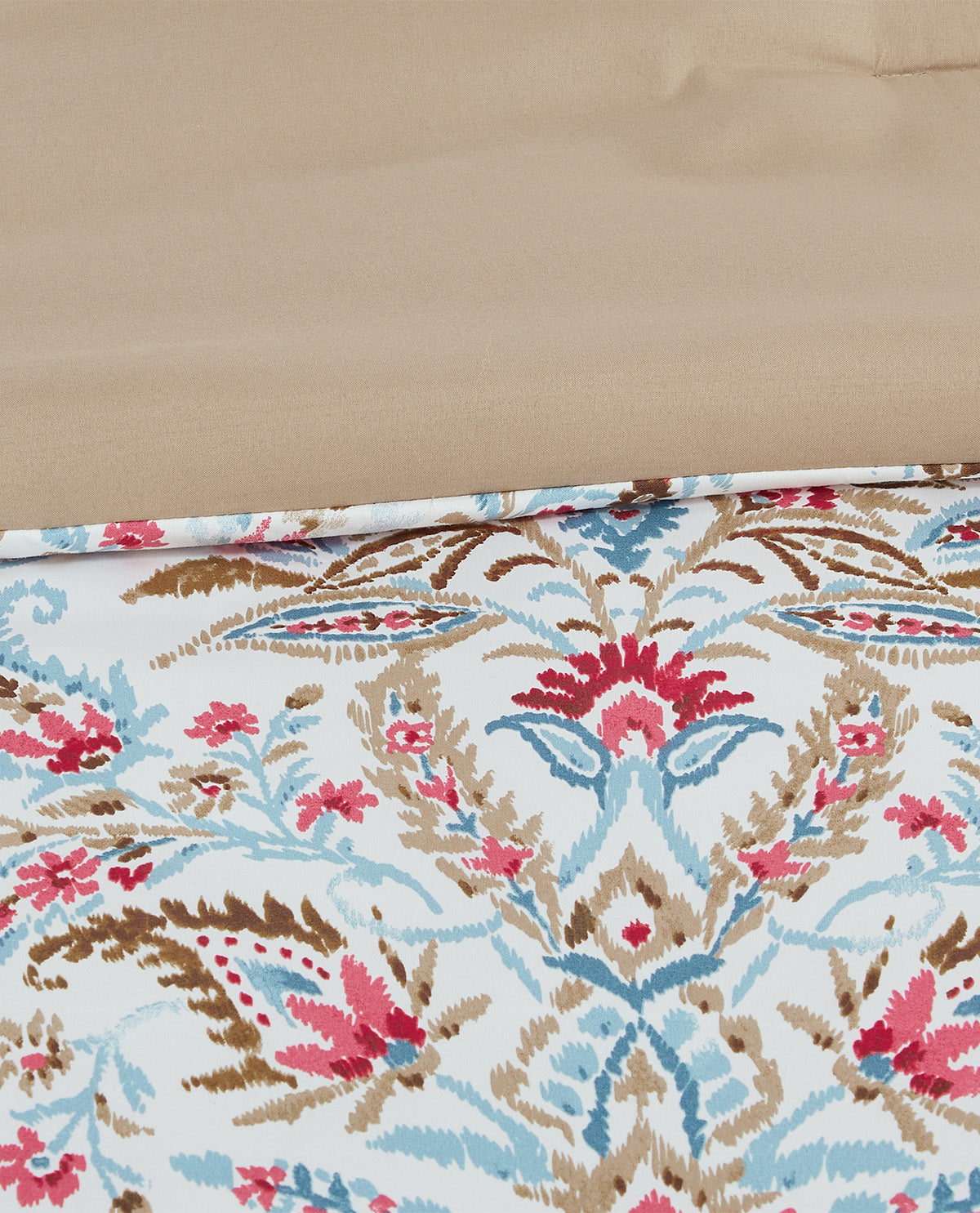 A close-up of a folded textile showing a white base with an ornate floral and botanical pattern in pink, light blue, and brown, with a plain beige section at the top.