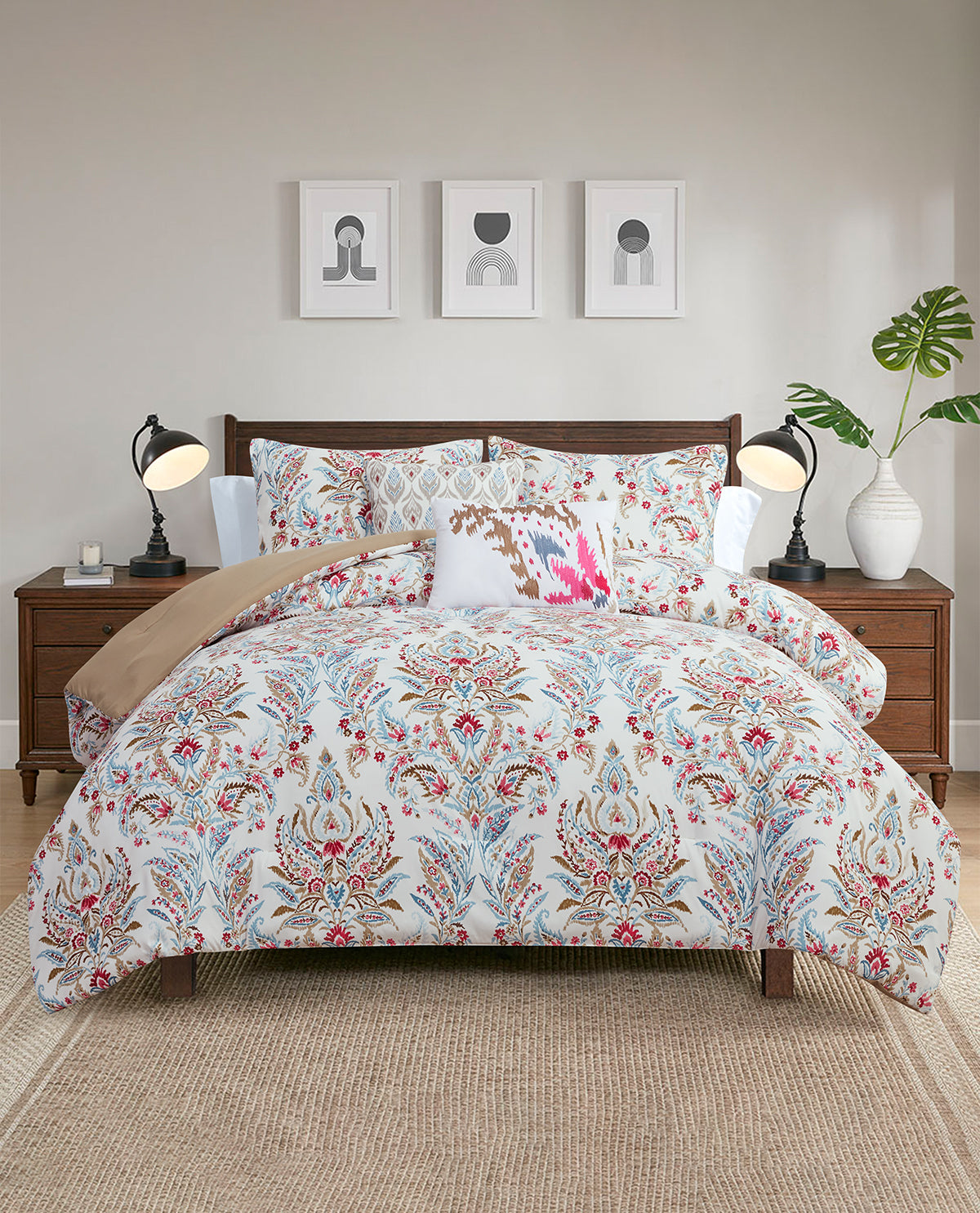 A bed dressed in a white duvet cover and matching pillow shams with an intricate multicolor floral and ornamental pattern, styled in a modern bedroom setting with wooden nightstands, lamps, and wall art.