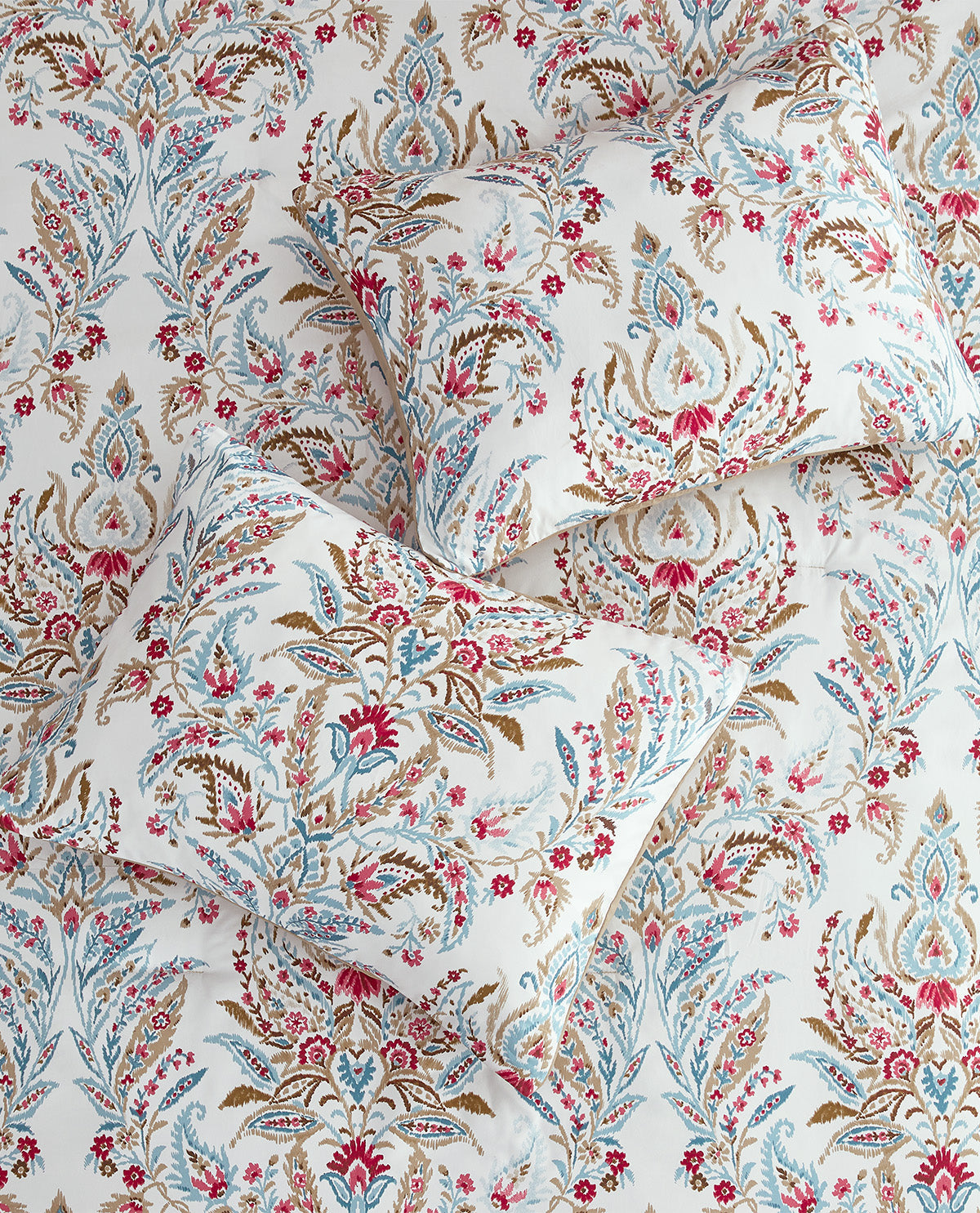 A close-up of patterned fabric with an ornate floral and paisley-style print on an off-white background, featuring blue, pink, and brown motifs.