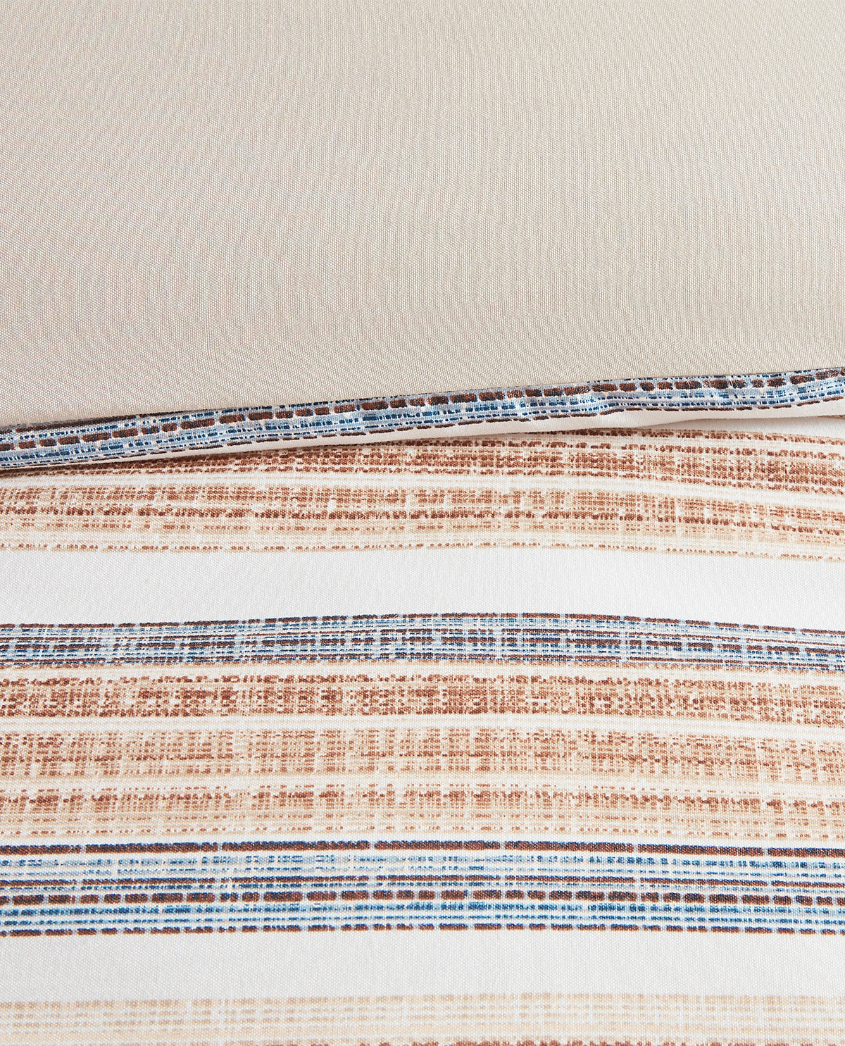 Close-up of woven fabric strips with horizontal stripes in blue, brown, and white, laid out on a light beige background.