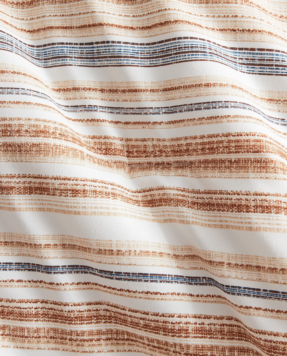 A close-up of a draped fabric with horizontal textured stripes in warm brown, beige, and dark blue on an off-white background.