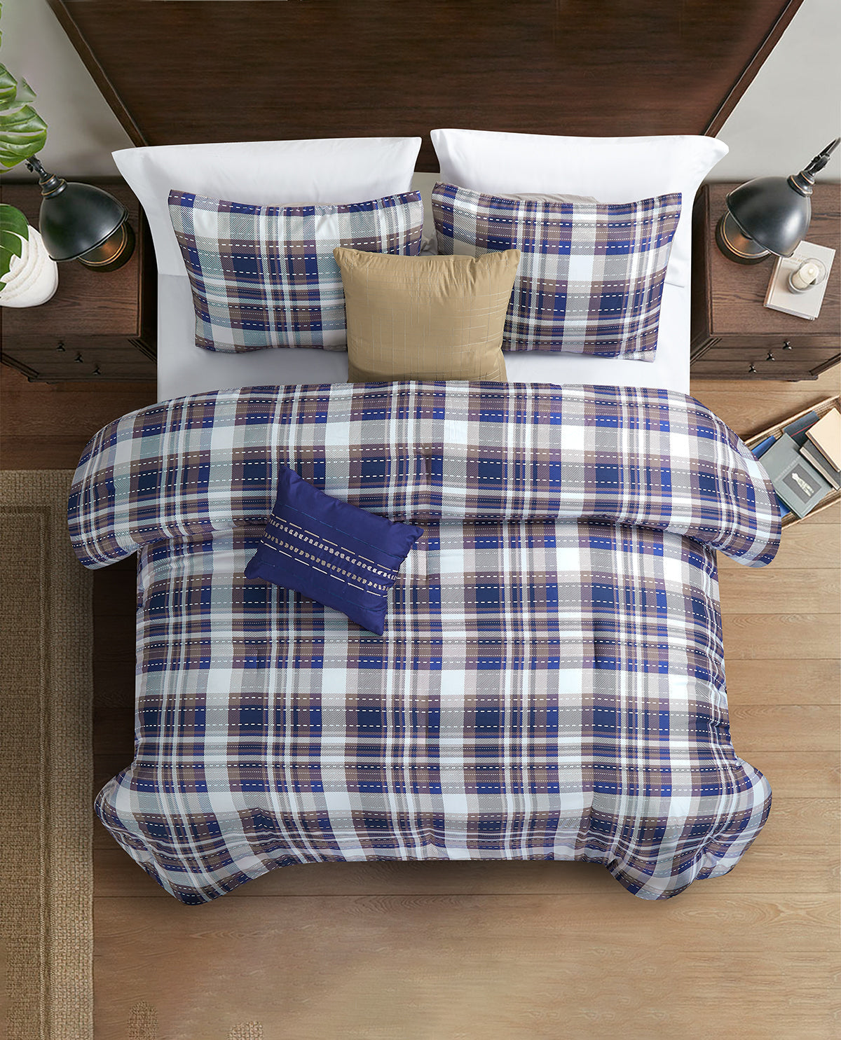 A top-down view of a bed styled with a blue, white, and beige plaid bedding set, including a duvet cover, two matching pillow shams, a beige accent pillow, and a small navy throw pillow, set against a dark wood headboard and nightstands.