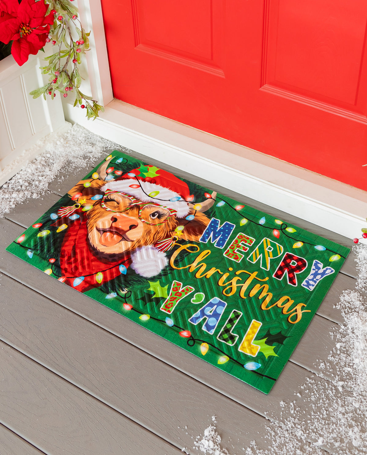 A festive Christmas doormat featuring a cartoon dog wearing a Santa hat and scarf, surrounded by colorful holiday lights and the text 'MERRY Christmas Y'all' on a green background, placed on a gray wooden porch in front of a red door.