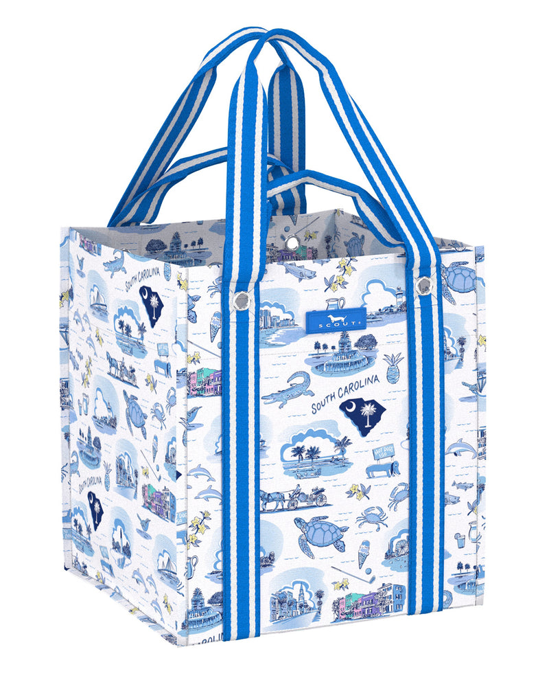 A reusable tote bag with a blue and white South Carolina coastal illustration print, featuring blue and white striped handles and a small blue brand label on the front.