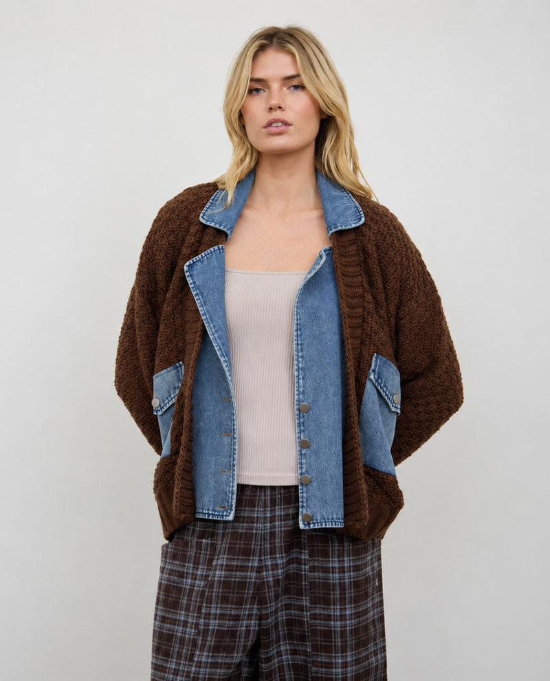 A woman modeling a brown fuzzy textured cardigan with light blue denim panels, worn over a beige ribbed tank top and brown plaid trousers, against a plain light gray studio background.