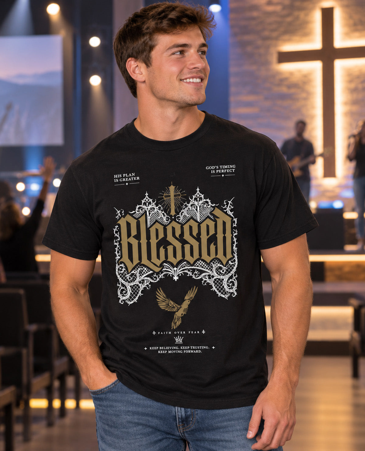 A smiling man wearing a black graphic t-shirt with a large 'Blessed' design in gold and white, standing in a church setting with a blurred background featuring a large cross and stage lights.