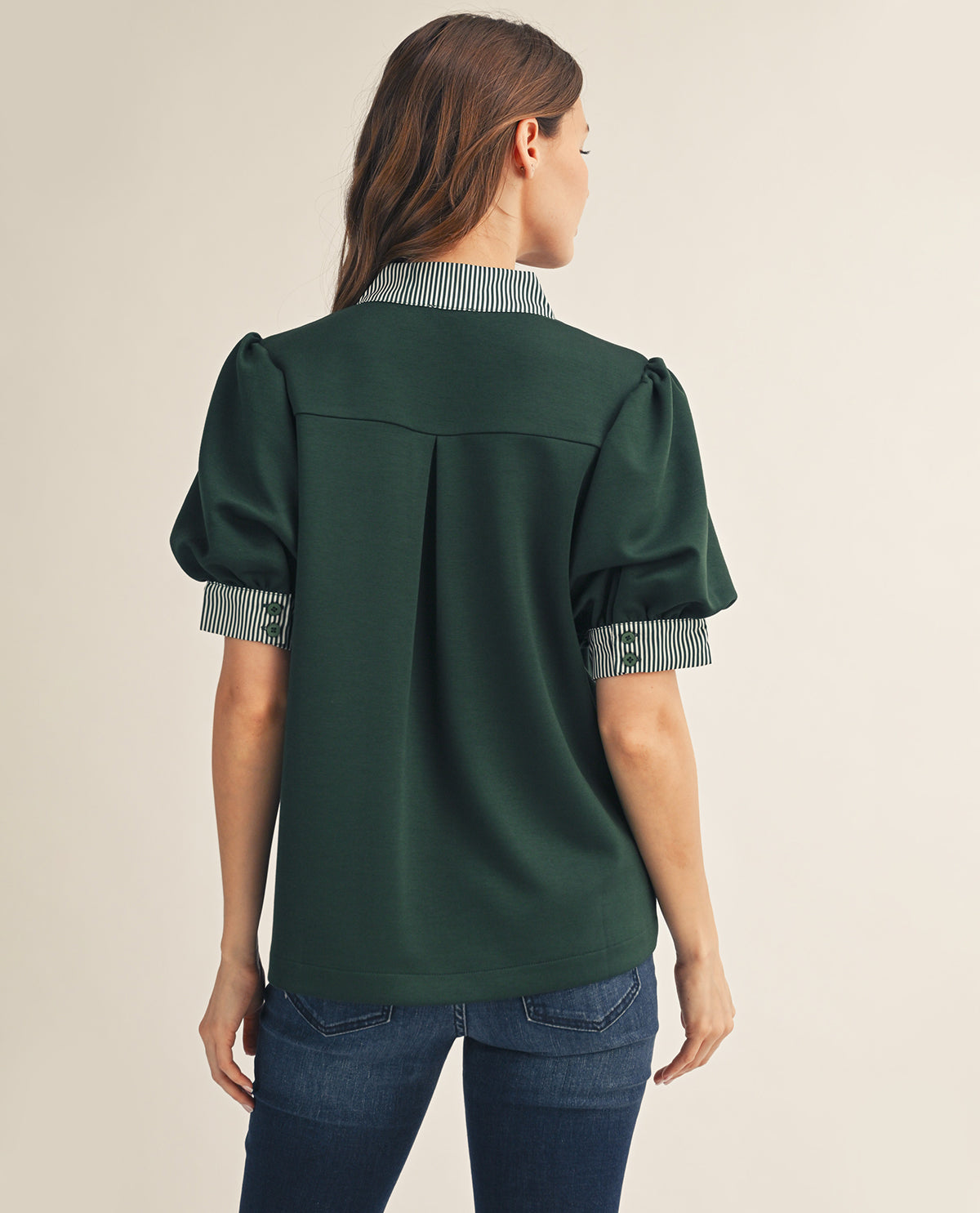 Woman wearing a green blouse with checkered trim on a beige background