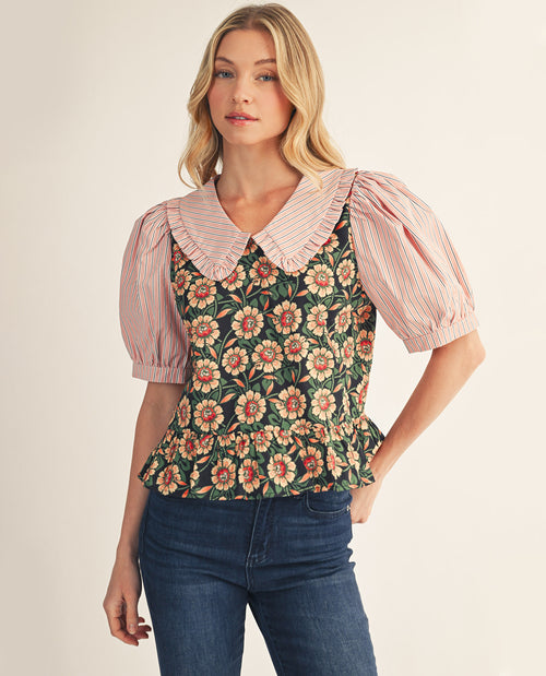 Woman wearing a floral top with a pink ruffled collar and puffed sleeves on a beige background