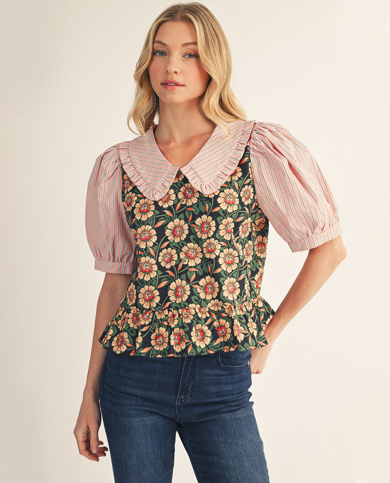 Woman wearing a floral top with a pink ruffled collar and puffed sleeves on a beige background