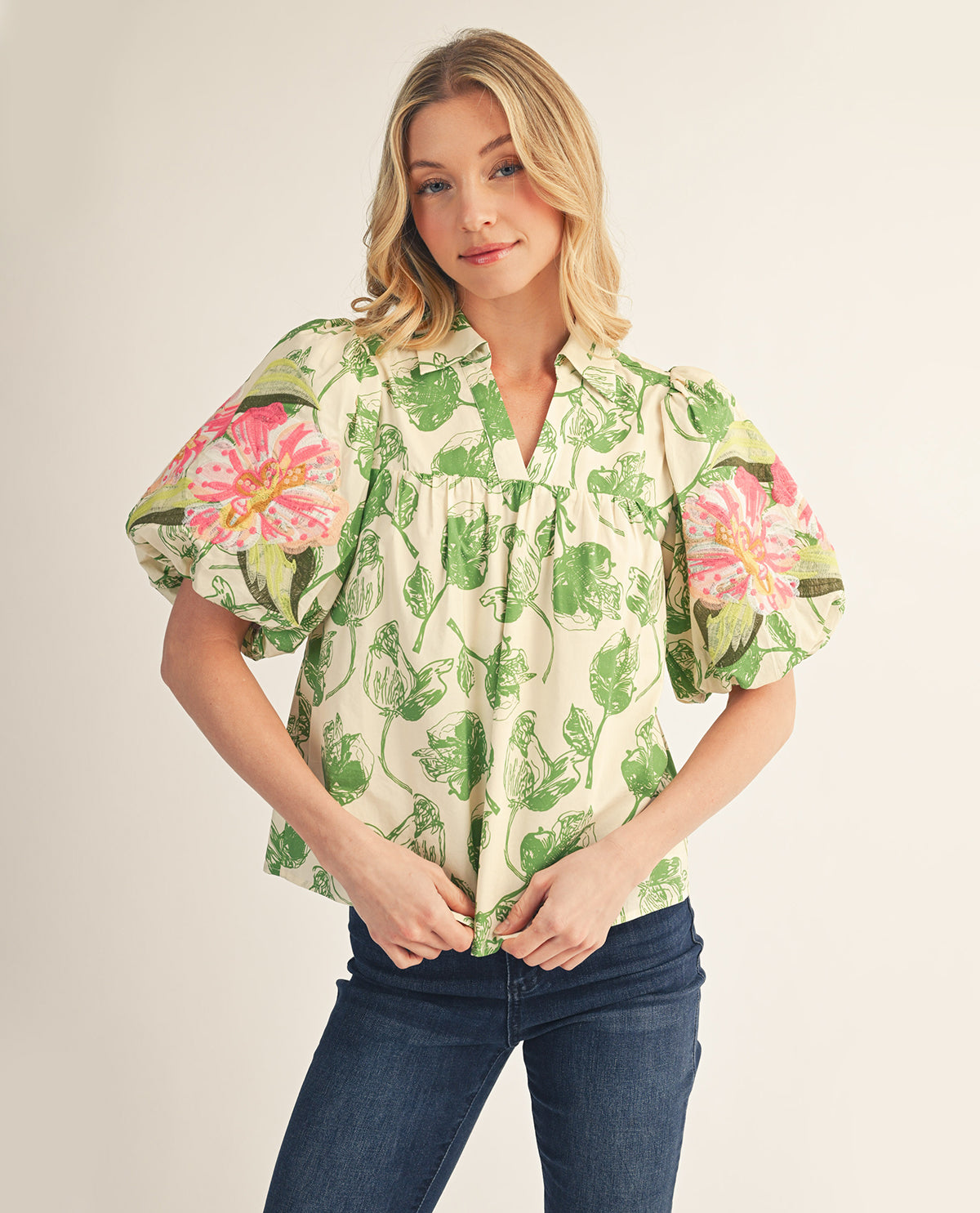 Woman wearing a floral blouse with puff sleeves on a plain background