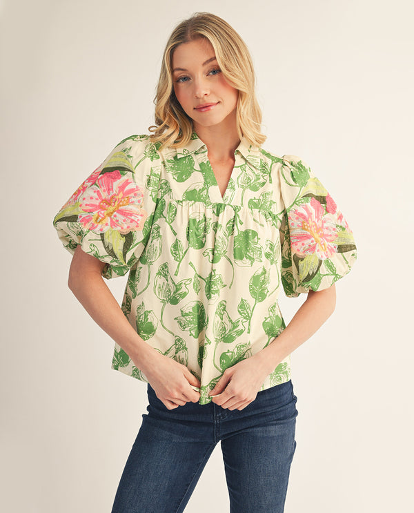 Woman wearing a floral blouse with puff sleeves on a plain background