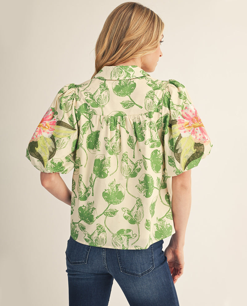 Woman wearing a floral blouse with green and pink patterns on a beige background