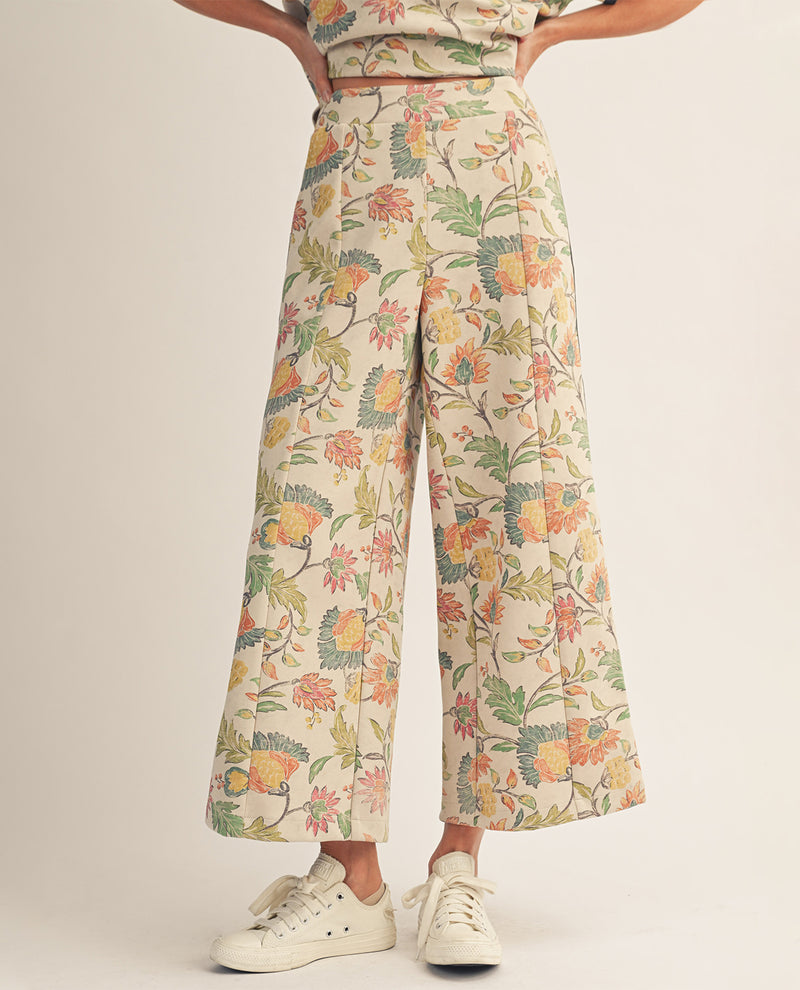 Person wearing floral wide-leg pants on a plain background
