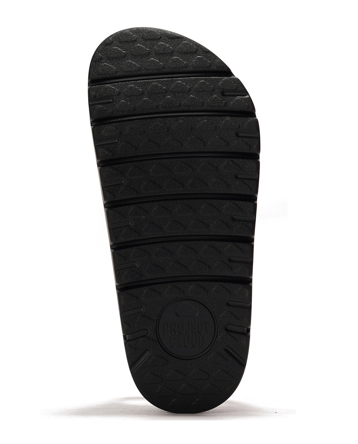 A close-up of a black textured outsole, showing the tread pattern and a circular embossed logo near the heel, set against a plain white background.